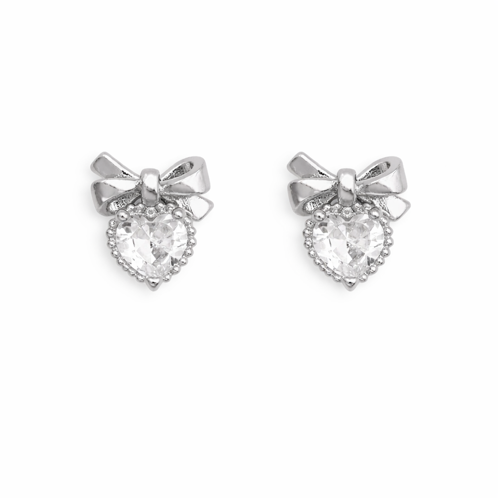 Silver bow-shaped nail charms with clear heart stones on a white background