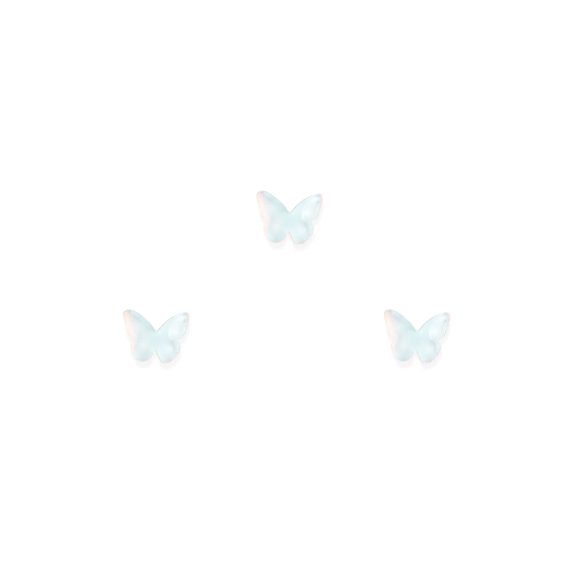 Three white butterfly-shaped nail charms on a white background