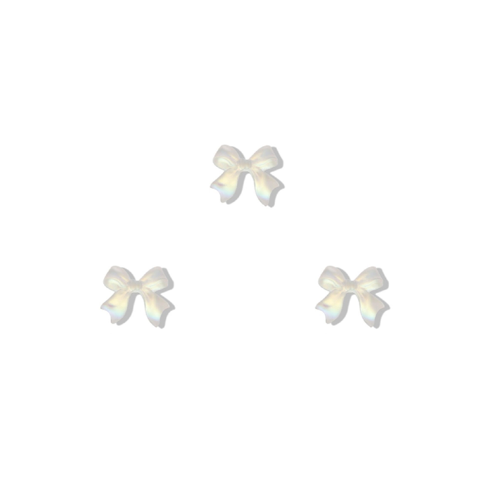 Set of three white bow-shaped nail charms on a white background